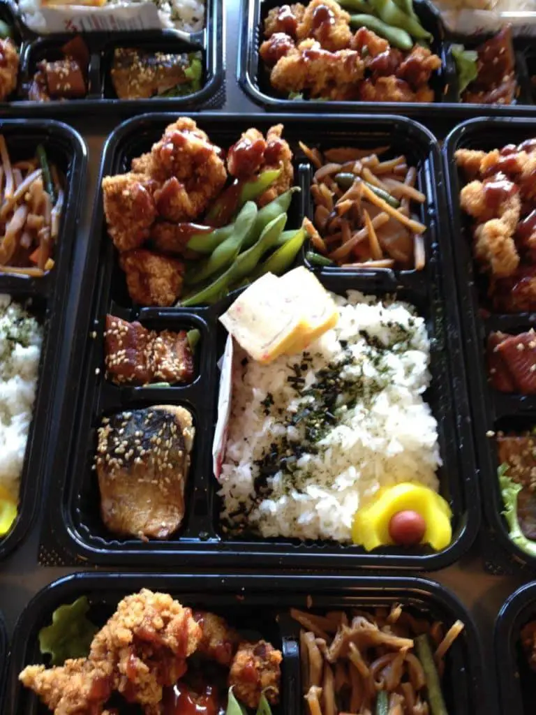 Bento Box from Puka Puka with rice topped with black sesame seeds, fish, chicken, green beans and salad