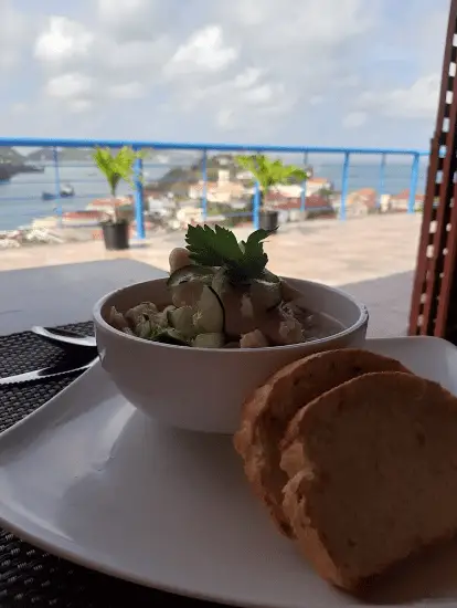 Bowl of creamy-looking dish with 2 slices of bread on a table in the foreground with an amazing view of the city in the background.