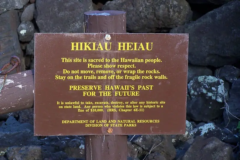 Sign that says: "Hikiau Heiau - This site is sacred to to the Hawaiian people. Please show respect. Do not move, remove, or wrap the rocks. Stay on trails and off the fragile rock walls. PRESERVE HAWAII'S PAST FOR THE FUTURE It is unlawful to take, excavate, destroy, or alter any historic site on state land. Any person who violates this law is subject to a fine of  $10.000. (HRS, Chapter  6E-11). Department of Land and Natural Resources Division of State Parks