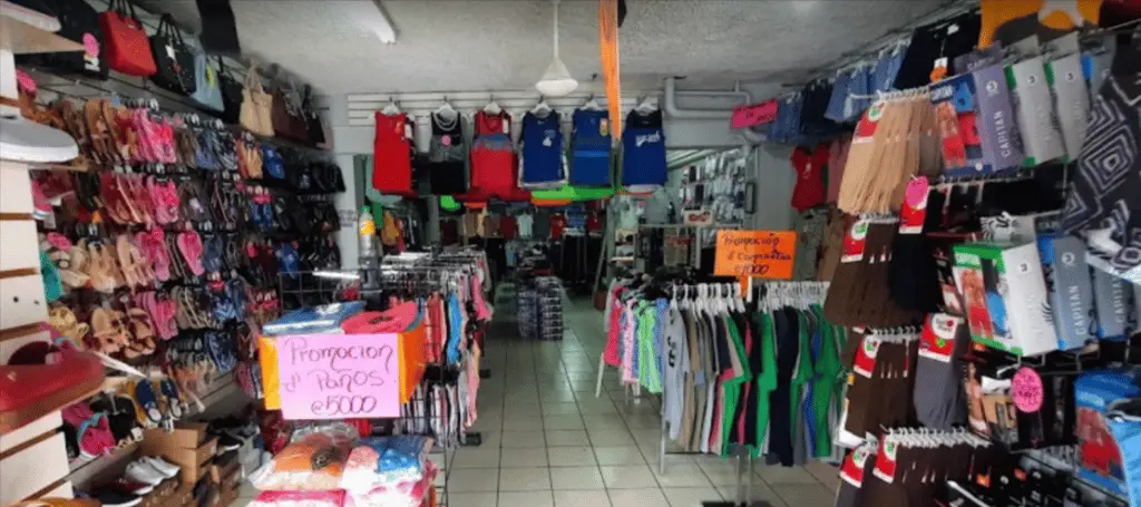 Interior of store with clothes on racks and hung on the back wall. 