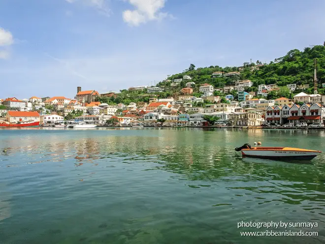 Taken from a boat in the water, the land rises is a large hill, with small colorful homes and buildings lining the hillside.