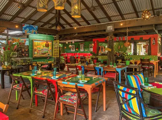 Inside Miss T's restaurant with colorful tables and chairs with a hut-like roof