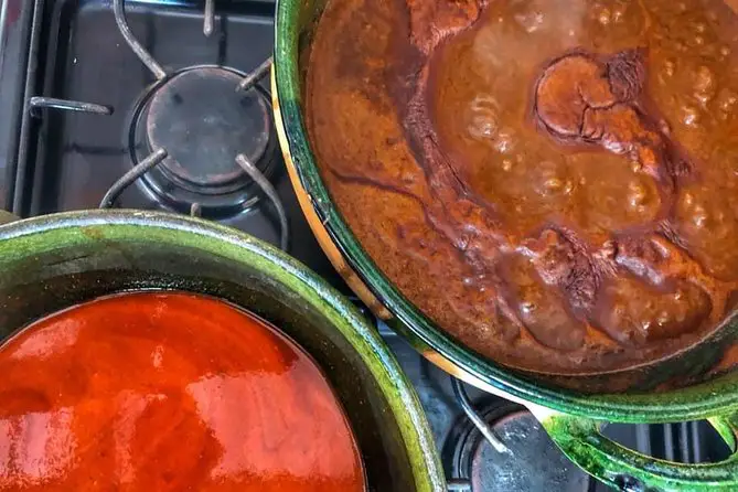 A close-up of 2 pots of sauces on a gas stove.