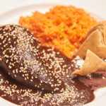 Mole poblano on a plate with rice and tortilla chips