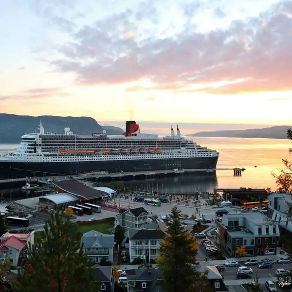 Aerial view of cruise ship docked in La Baie, Saguenay. It is sunset in the background with the town in the foreground.