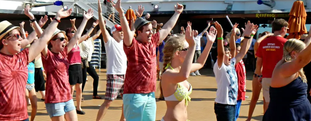 People dancing on cruise deck. Their arms are in the air like they forming the "Y" to the song "YMCA"