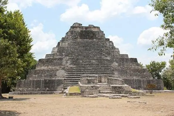 Large stone pyramid-shaped temple with many stairs leading to the peak where there is a cave-like opening.