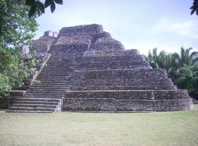 Pyramid-shaped stone temple with stairs lining the sides. The top appears to be cut off, revealing a wide flat base instead of a peak. 