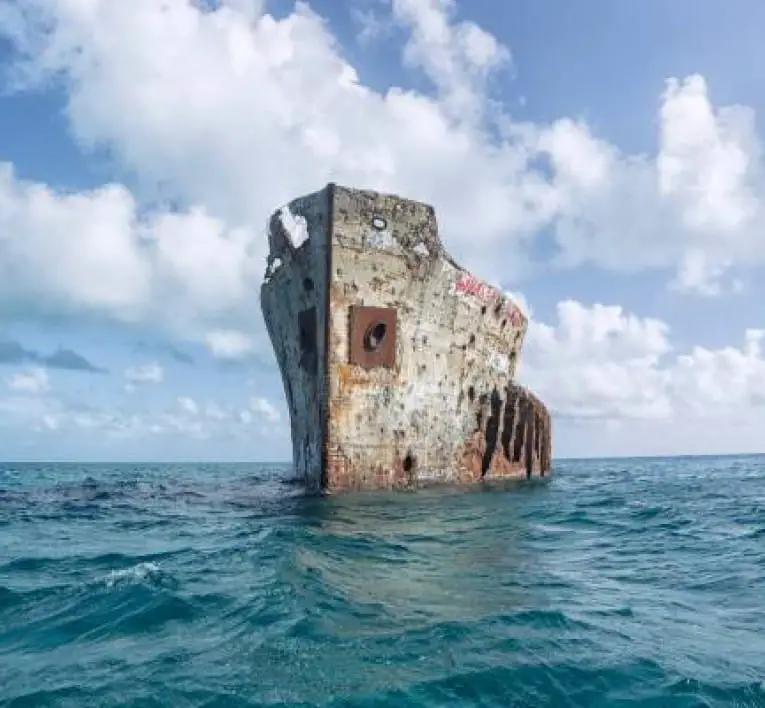 Rusty hull of the shipwreck SS Sapona sticking out of the ocean water