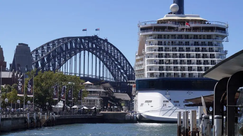 Large cruise ship docked in Sydney Australia beside a large bridge