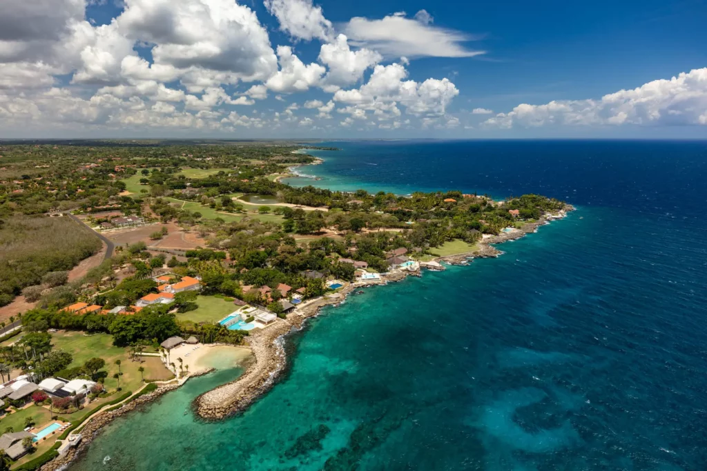 Aerial view of part of Casa de Campo resort with ocean and pool, beach and resort villas dotting the shore.