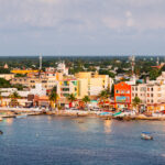Skyline of Cozumel coast, with a view from the water. Buildings are colorful and a maximum of 5 stories tall.