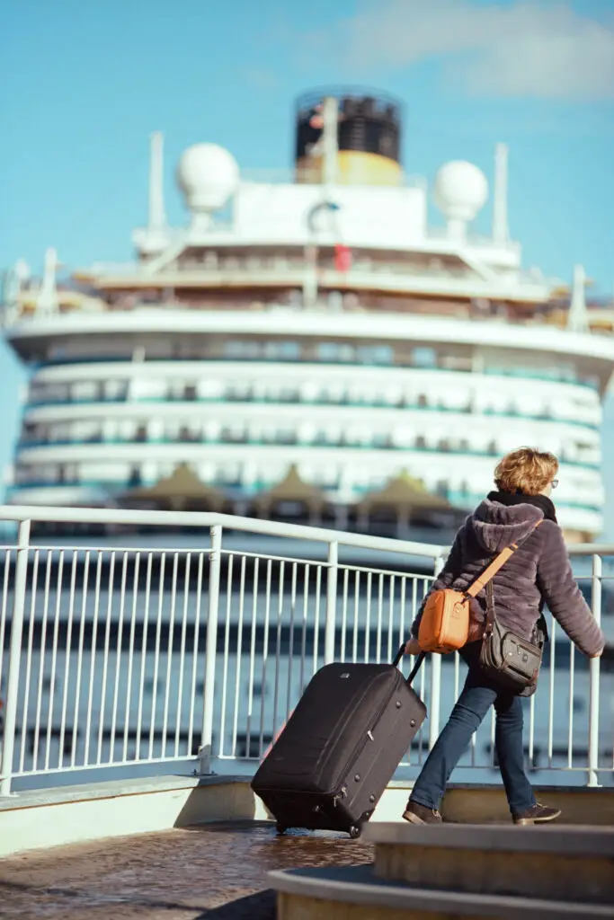 Woman pulling a suitcase with a cruise ship in the background