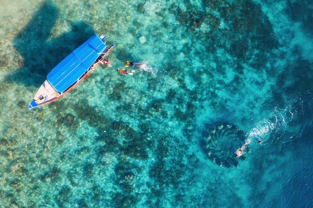 Cozumel small boat on the water from above with people in the water